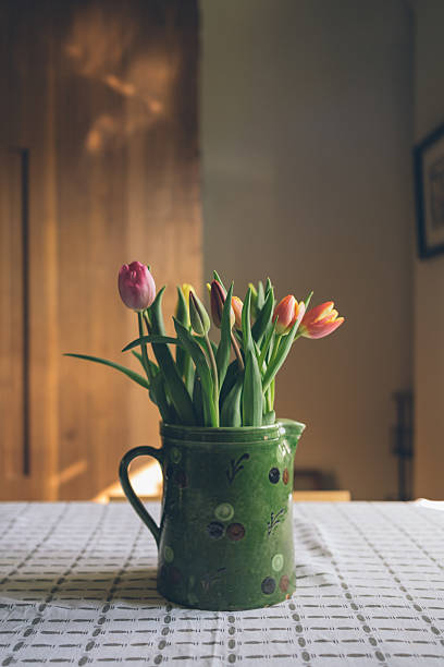 Fresh tulips in an old teapot on a table