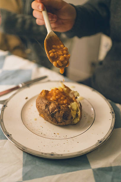 Man prepares to eat baked beans on baked potato