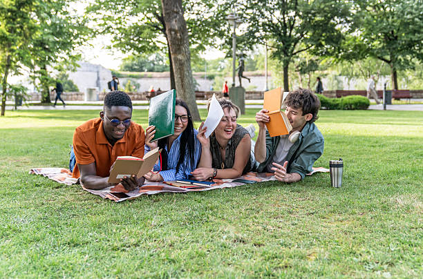 istock Cheerful students lying on grass reading and having fun 2217502750