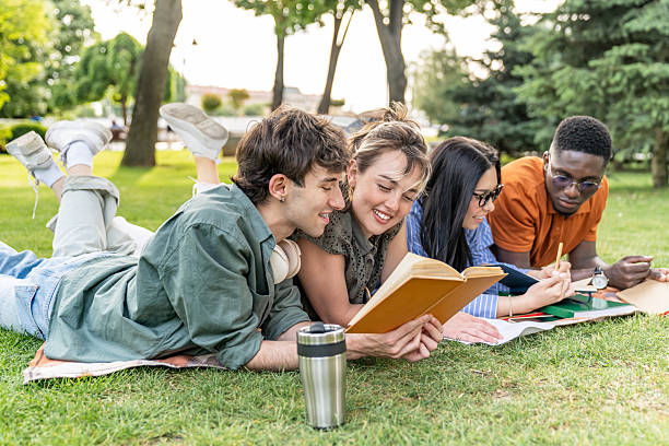 istock Students lying on grass reading and studying together in park 2217503762
