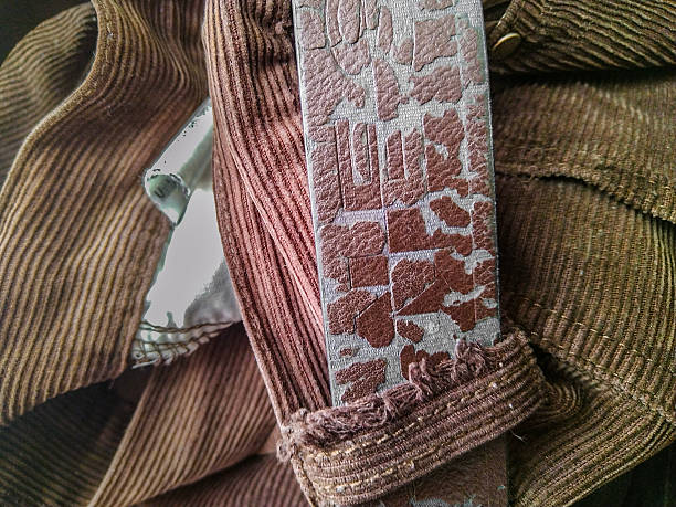 A close-up shot from a high angle showing a folded set of clothes and a textured leather belt.