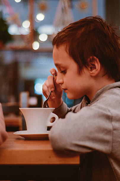 istock Thoughtful Boy Enjoying a Warm Beverage in Cozy Cafe 2217509230