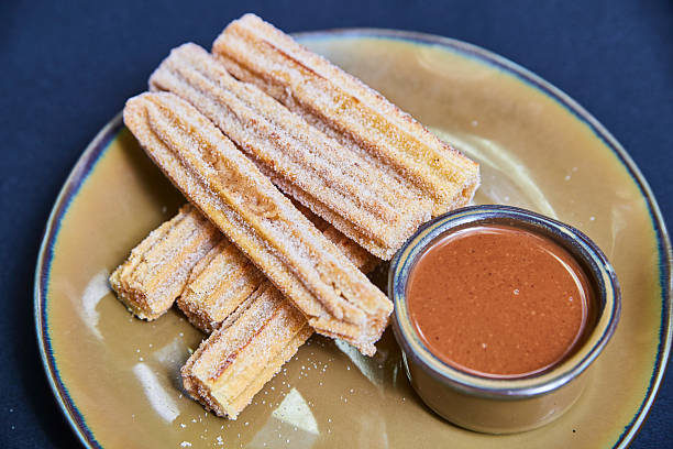 istock Fresh Churros with Chocolate Sauce on Rustic Plate 2217513044