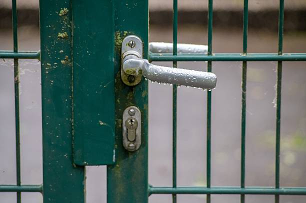 Rain drops clinging to a metal door handle on a green metal gate after a rain shower
