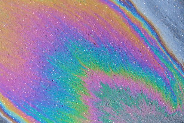 istock Rainbow-colored oil slick shimmers on rough asphalt, creating an abstract pattern with vivid hues and sparkling texture in natural daylight. 2217515045