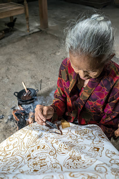 istock Indonesian woman drawing traditional batik pattern on fabric 2217520231