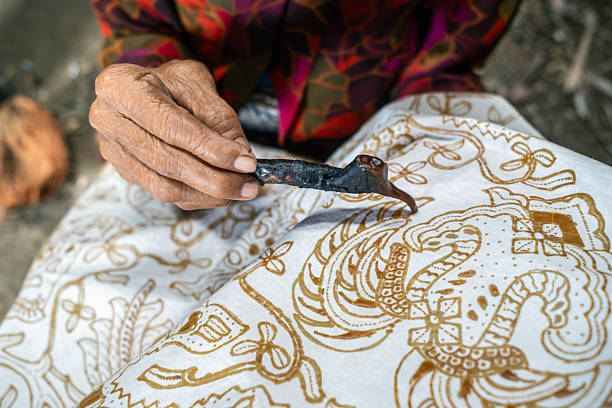 istock Indonesian artisan drawing traditional batik pattern on fabric with canting 2217520500