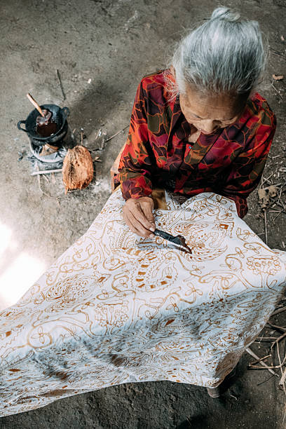 istock Indonesian artisan drawing traditional batik pattern on fabric 2217520557