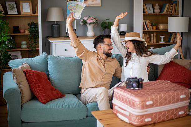 istock Excited couple celebrating upcoming trip with maps and suitcase 2217521966