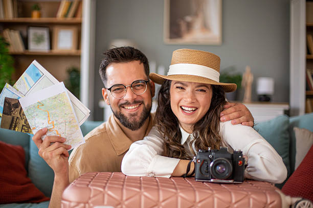 istock Young couple smiling and planning their next trip with maps and camera 2217522308
