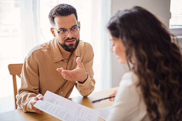istock Young couple analyzing contract terms together with financial advisor 2217523995