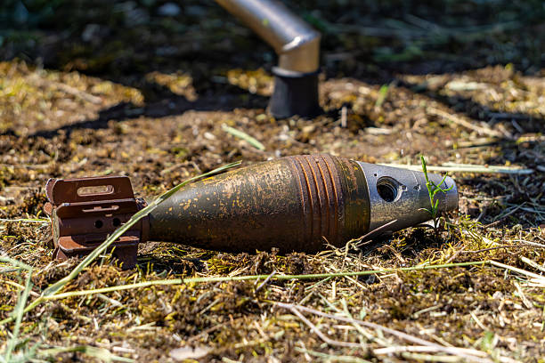 istock old, rusted mortar shell lying on dry soil with some grass. The object appears weathered and potentially dangerous, suggesting a military or historical context. 2217525300