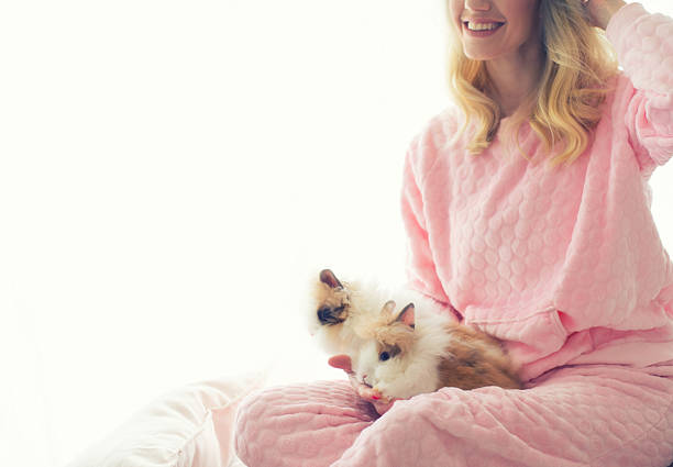 Beautiful young woman holding a small rabbit at home and playing with it.
