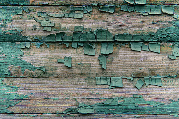 Close-up of peeling paint on an old wooden surface. Cracks and layers reveal aged texture and natural decay, creating an abstract rustic composition.