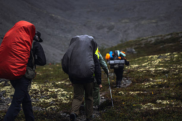 Group of hikers carrying backpacks navigating a mountainous trail. Exploring nature's rugged beauty.