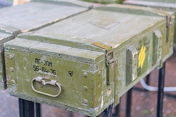Stack of weathered metal containers, possibly shell crates, with numbers 507-56198 and 1184-6264 The containers have visible bolts, rivets, and a yellow signsticker The scene is outdoors, with a s