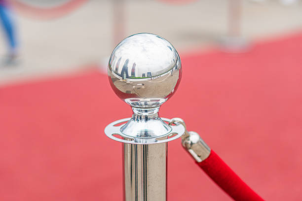 istock Red carpet event, blurred figures, trophy with shiny sphere, red velvet rope, central focus on the trophy 2217531932