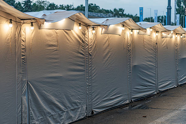 istock Row of white canvas tents illuminated by string lights at night, dark sky above 2217532267