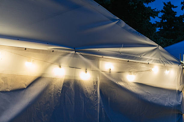 Nighttime outdoor scene with a lit white tent, featuring string lights around the upper perimeter No discernible people or text