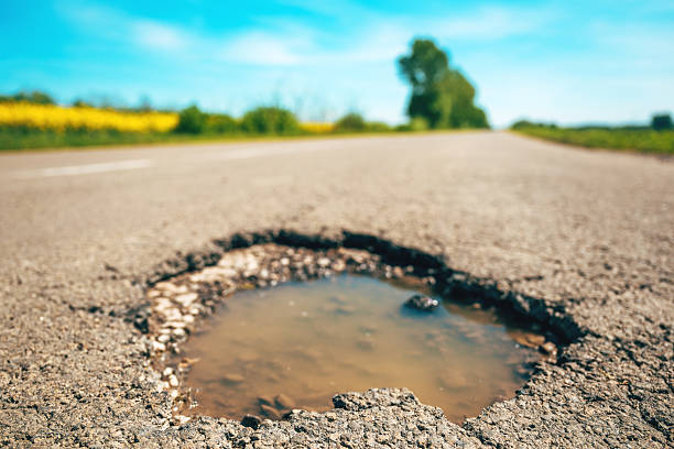 istock Large pothole in asphalt road surface, hole in a country road 2217532911