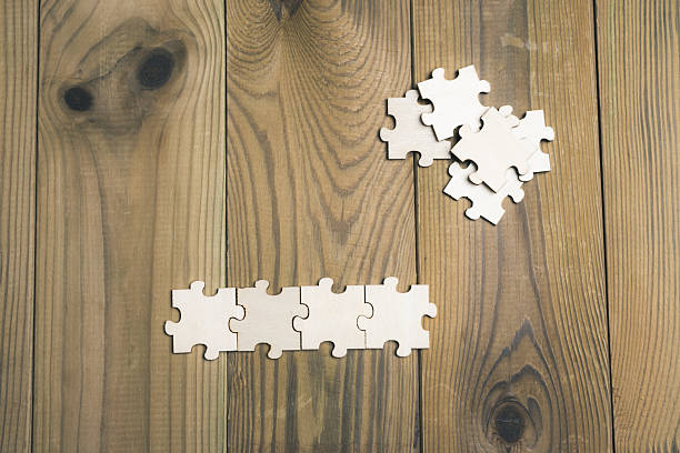 istock Puzzle pieces scattered across a wooden board. 2217536000
