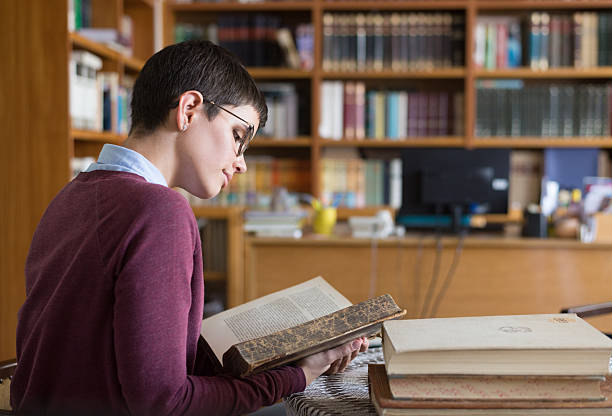 istock Woman reading books and studying in the library 2217536779