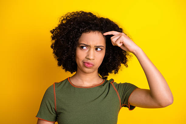 istock Young woman in a thoughtful pose on yellow background making a pointing gesture with a contemplative facial expression 2217536917