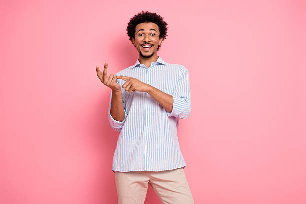 istock Confident young man gesturing with excitement while posing against pink backdrop in a trendy casual outfit 2217538488