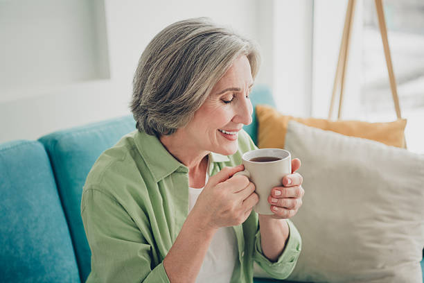 istock Charming elderly woman enjoying a cup of tea while relaxing on a cozy couch in a bright living room setting 2217539204