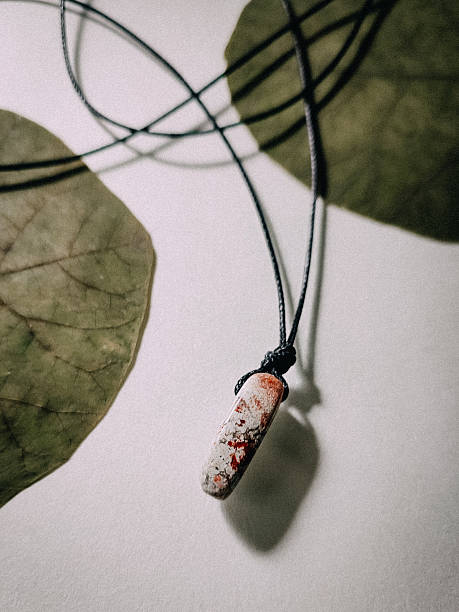 istock Natural needle shape pink jasper healing crystal, Adjustable black cord small stone pendant choker, energy gemstone, Minimalist necklace jasper at white background with leaves, Handmade jewelry close 2217540632