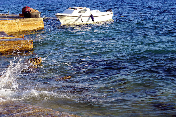 Small white boat floating on the sea surface during the strong south wind in the Croatian coast