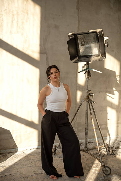 A white woman stands barefoot near a studio light