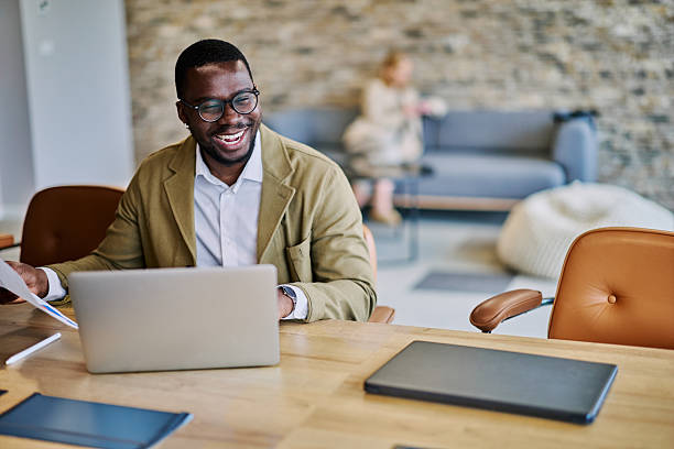 istock Smiling businessman working on laptop and checking documents in modern office 2217544303