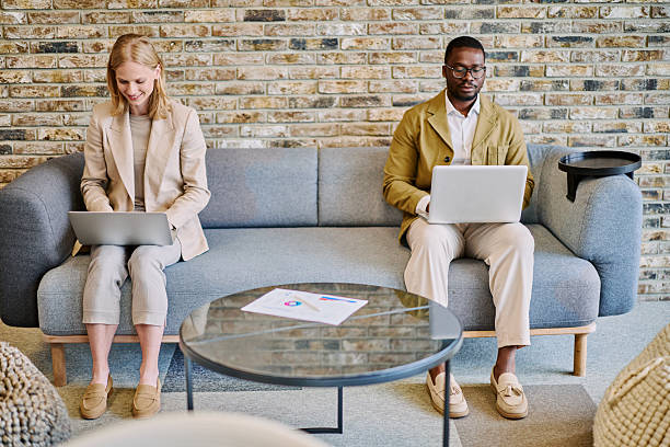istock Business people working on laptops in modern office lobby 2217544358