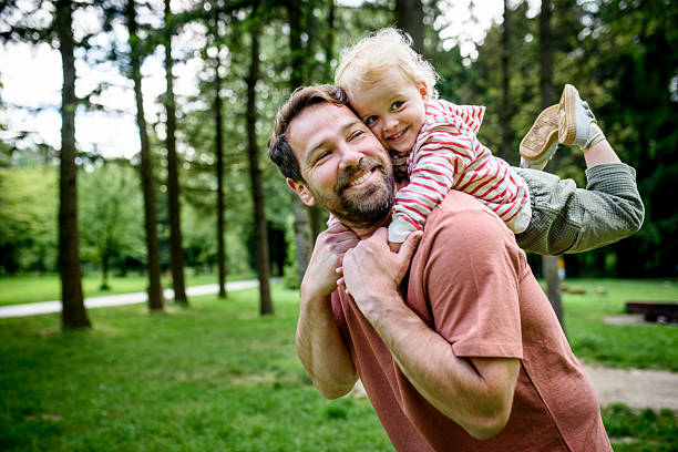 istock Father carrying his smiling son on shoulders during walk in park 2217545383