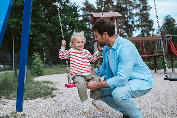istock Father swinging small son on playground swing. 2217545548
