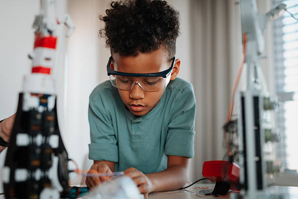 istock Focused boy working on small robot toy at home. 2217547514