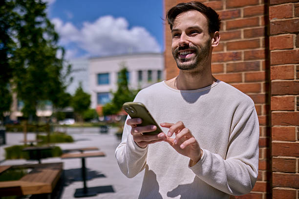 istock Young man smiling and using mobile phone in the city 2217548883