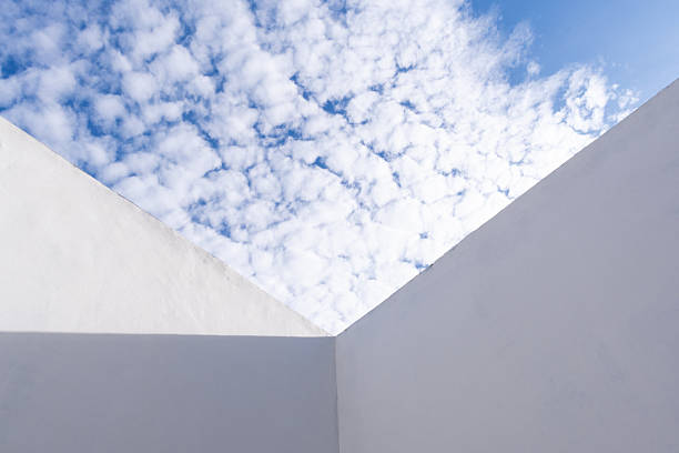 A symmetrical white triangle wall standing against a clear blue sky, creating a striking contrast between architecture and nature