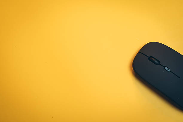 istock Modern Black Wireless Mouse on Vibrant Yellow Background for Creative Technology and Workspaces 2217550452