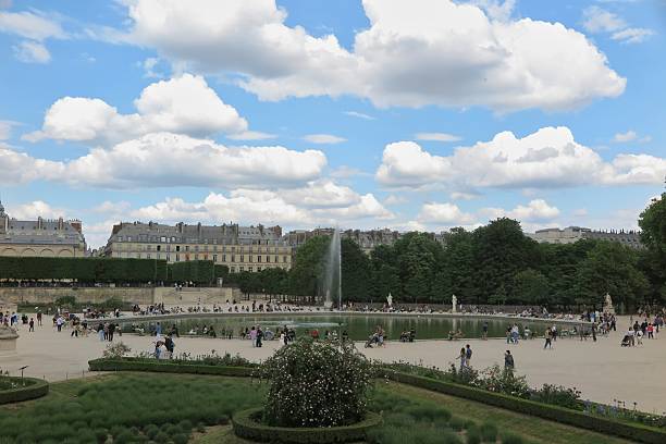 Paris, France - May 11, 2025:  People gather around the Tuileries Garden fountain near the Louvre Museum on the  Right Bank of the Seine River.