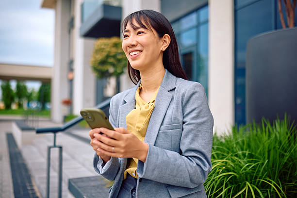 istock Young businesswoman using smartphone outside office building 2217555171