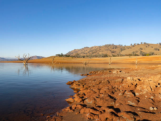 istock Morning sunlight on rocky red dirt next to reflection lake 2217556470