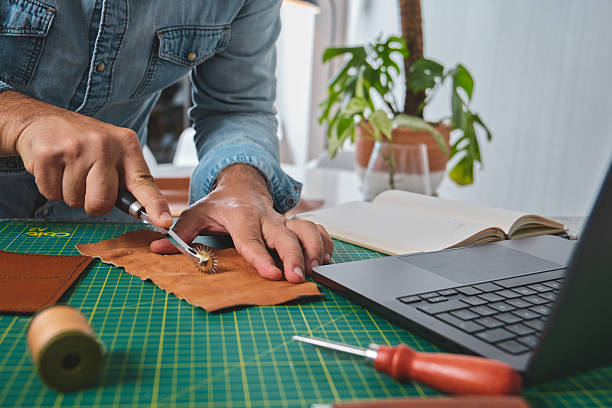 istock Shoemaker working leather at home with laptop and tools 2217557753