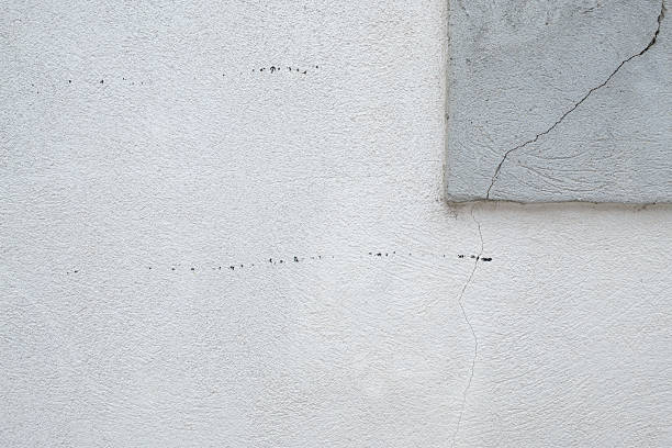 istock Cracked white wall with textured surface and right angle concrete accent showcasing aging and structural issues 2217560548