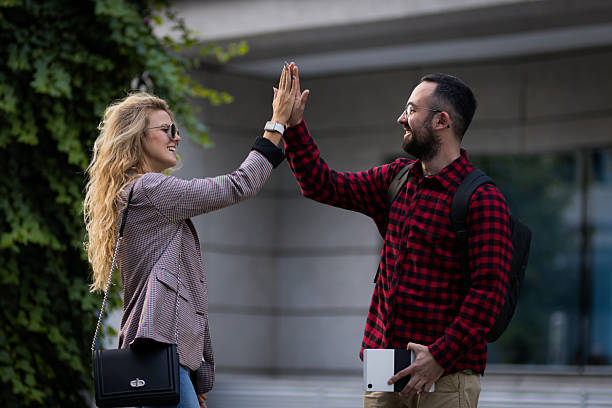 istock Happy friends greeting each other with a high-five outdoors, showcasing a fun and joyful moment. Smiling young adults enjoying a day outside, capturing their cheerful friendship and positive energy 2217561735
