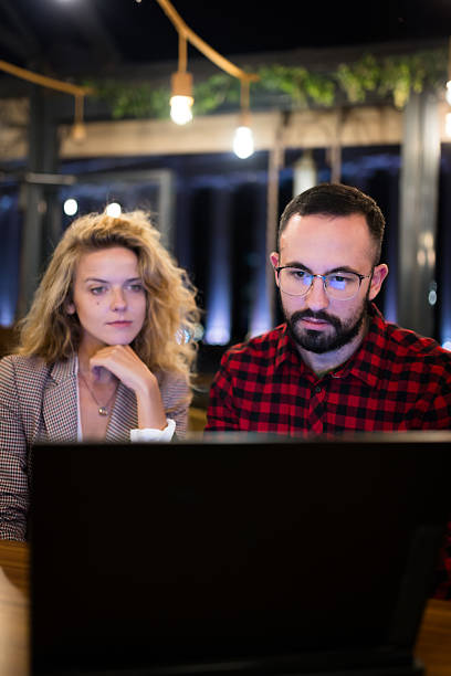 istock Focused professionals collaborating on a project on a laptop in a modern office space during night time, highlighting teamwork and dedication under ambient lighting 2217561826