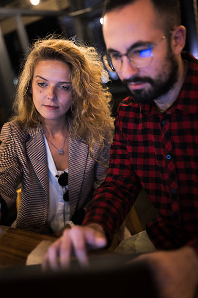 istock Focused young professionals collaborating at a laptop in a cozy office space, discussing strategies with serious expressions, highlighting teamwork, concentration, and modern work environment, ideal for business or technology themes. 2217561837