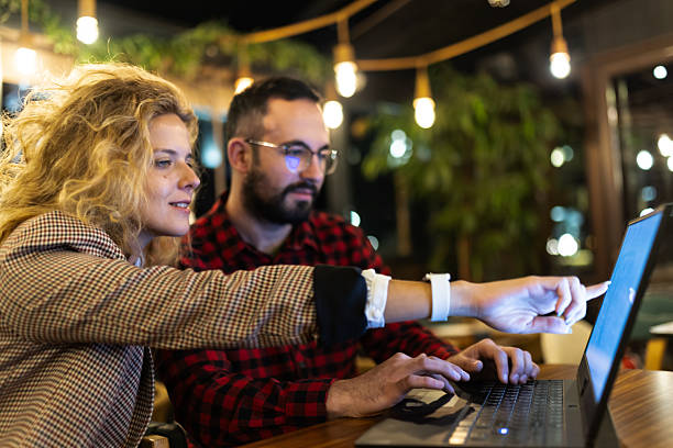 istock Two colleagues collaborating on a project while working on a laptop in a cozy cafe with ambient lighting, showcasing teamwork and creativity in a relaxed work environment. 2217561844