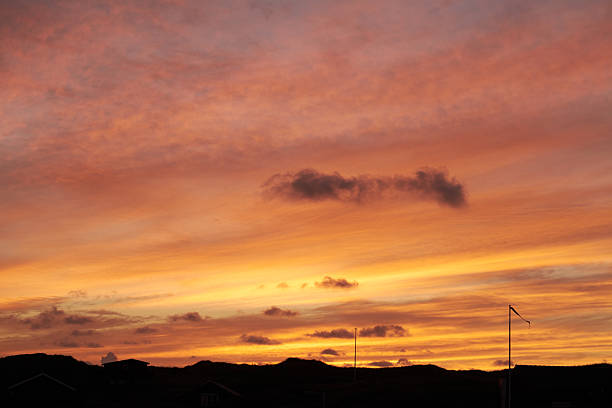 A magical sunset painting the sky with vivid orange and golden tones, scattered clouds adding texture, and silhouetted structures providing depth. A stunning visual treat depicting nature's artistry.